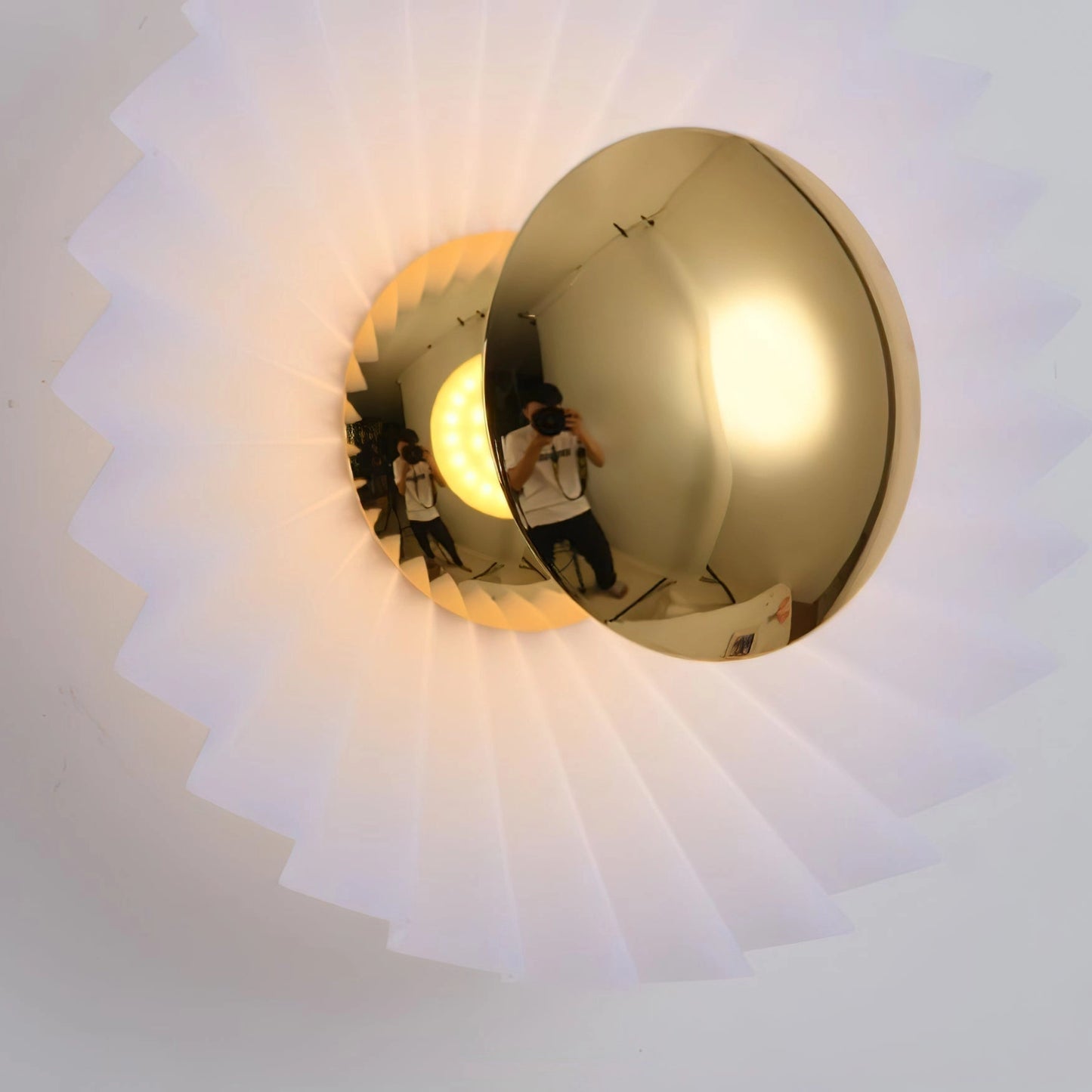Modern wall lamp with artistic design, featuring a circular light fixture, mounted on a wall.