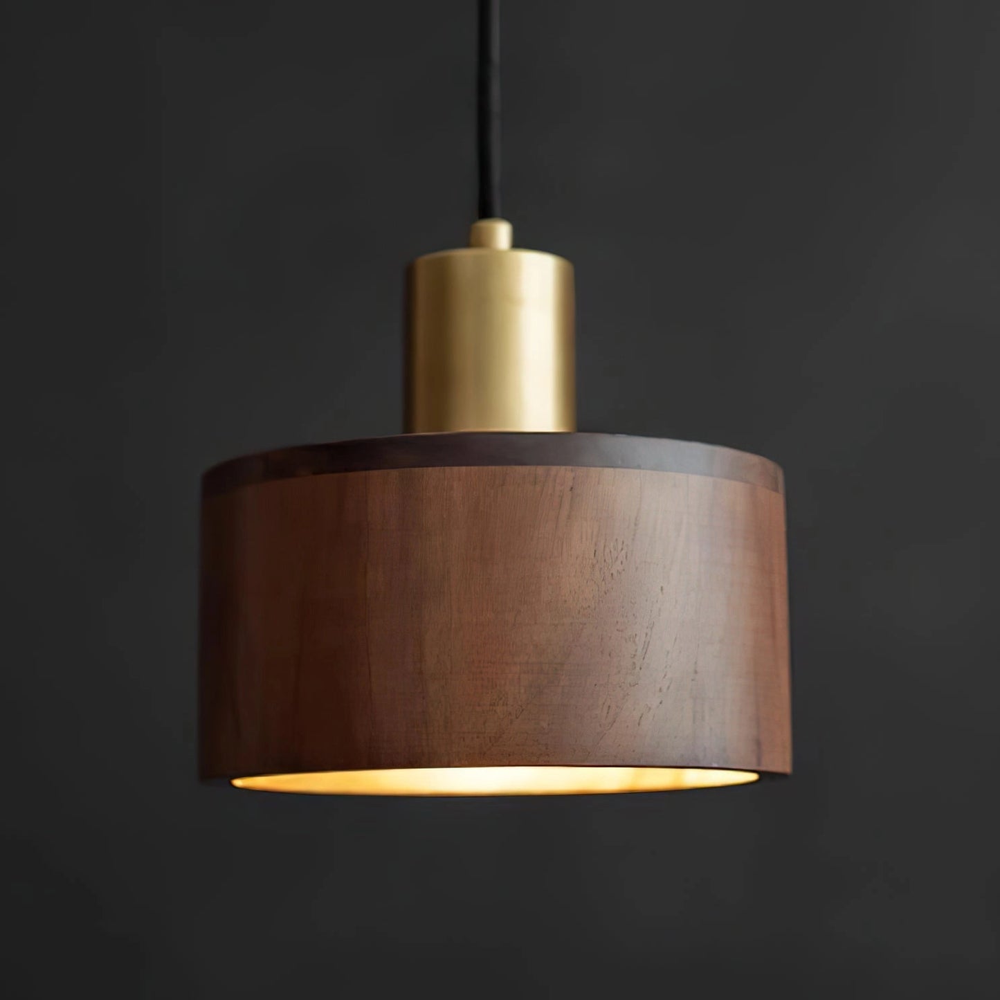 Walnut wood pendant lamp inspired by Japanese woodworking, featuring a cylindrical wooden body, a metal accent, and a circular lampshade, hanging from the ceiling.
