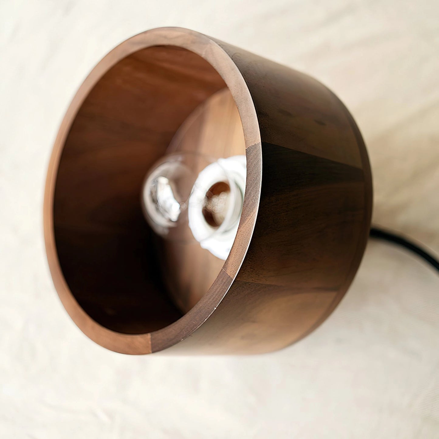 Walnut wood pendant lamp with Japanese woodworking design, circular plywood structure, and metal accents, hanging from the ceiling.