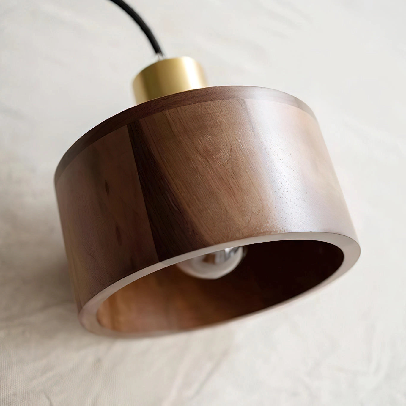 Walnut wood pendant lamp inspired by Japanese woodworking, featuring a circular wooden design with a sleek metal fixture hanging from the ceiling.