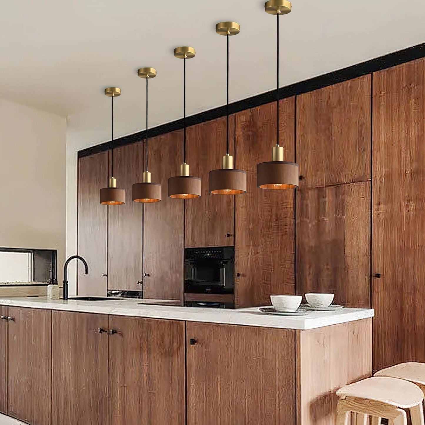 Walnut wood pendant lamp inspired by Japanese woodworking, hanging from the ceiling in a modern kitchen with wooden cabinetry and countertops.