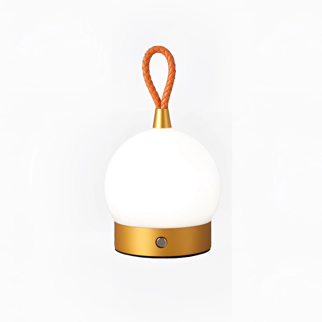 Waterproof LED Table Lamp in cordless orb design with gold accents, displayed on a wooden surface near a tree and decorative ornaments, radiating a warm glow.