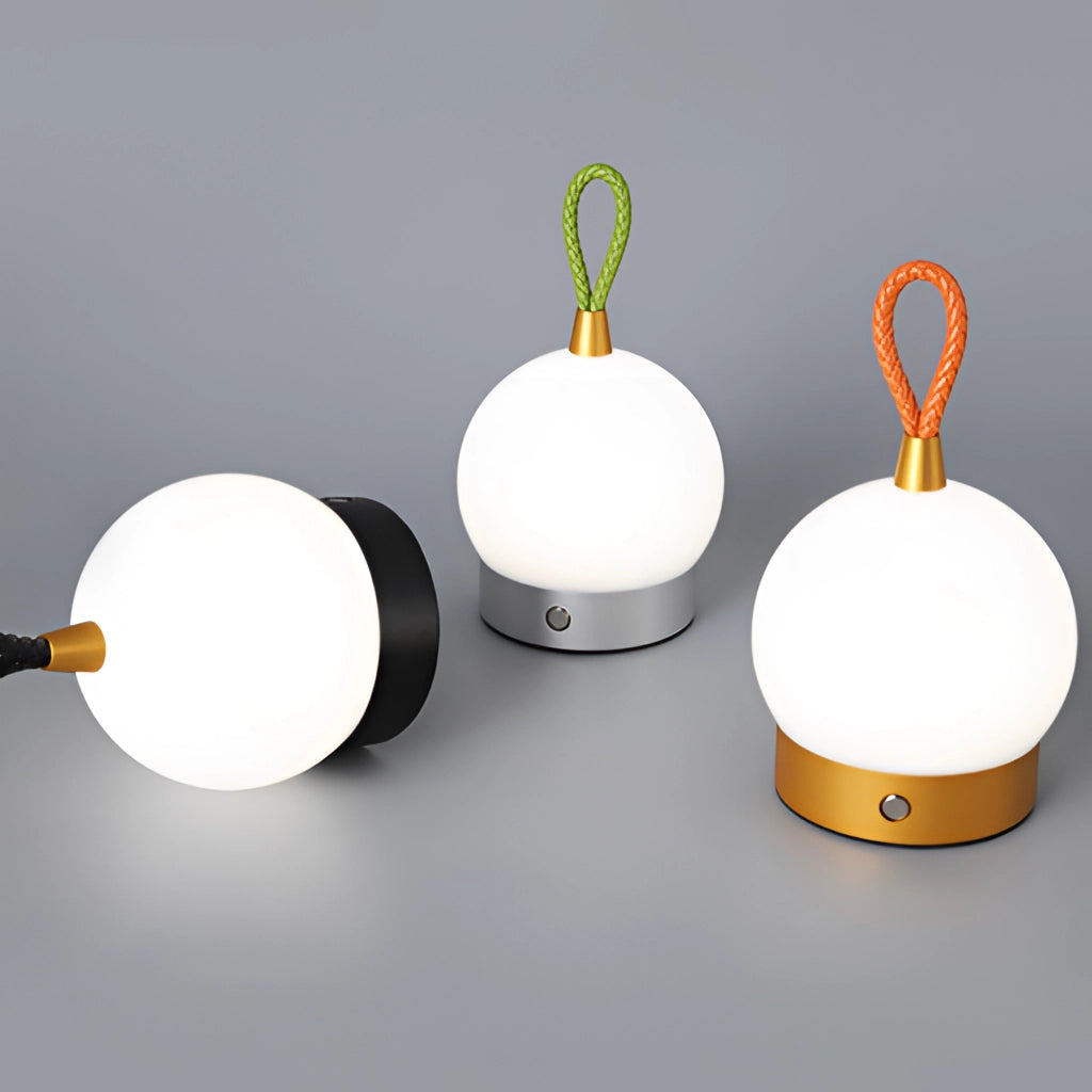 Waterproof LED table lamp with a cordless orb design, emitting soft light, placed on a table surrounded by plants.