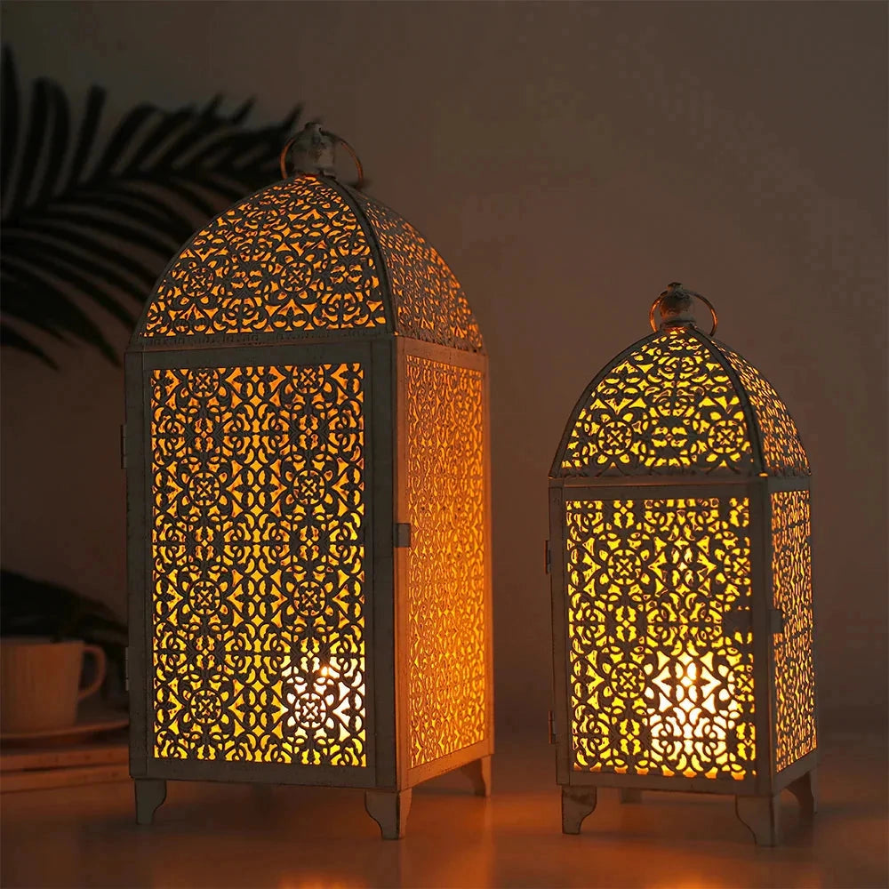 Set of two white gold metal candle lanterns with arched tops, symmetrical design, and amber-tinted glass panels. Perfect for indoor and outdoor decor.