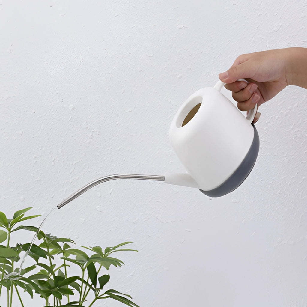 A person holding a modern and functional April Showers garden watering can, with plants and flowers in the background against a clear sky.