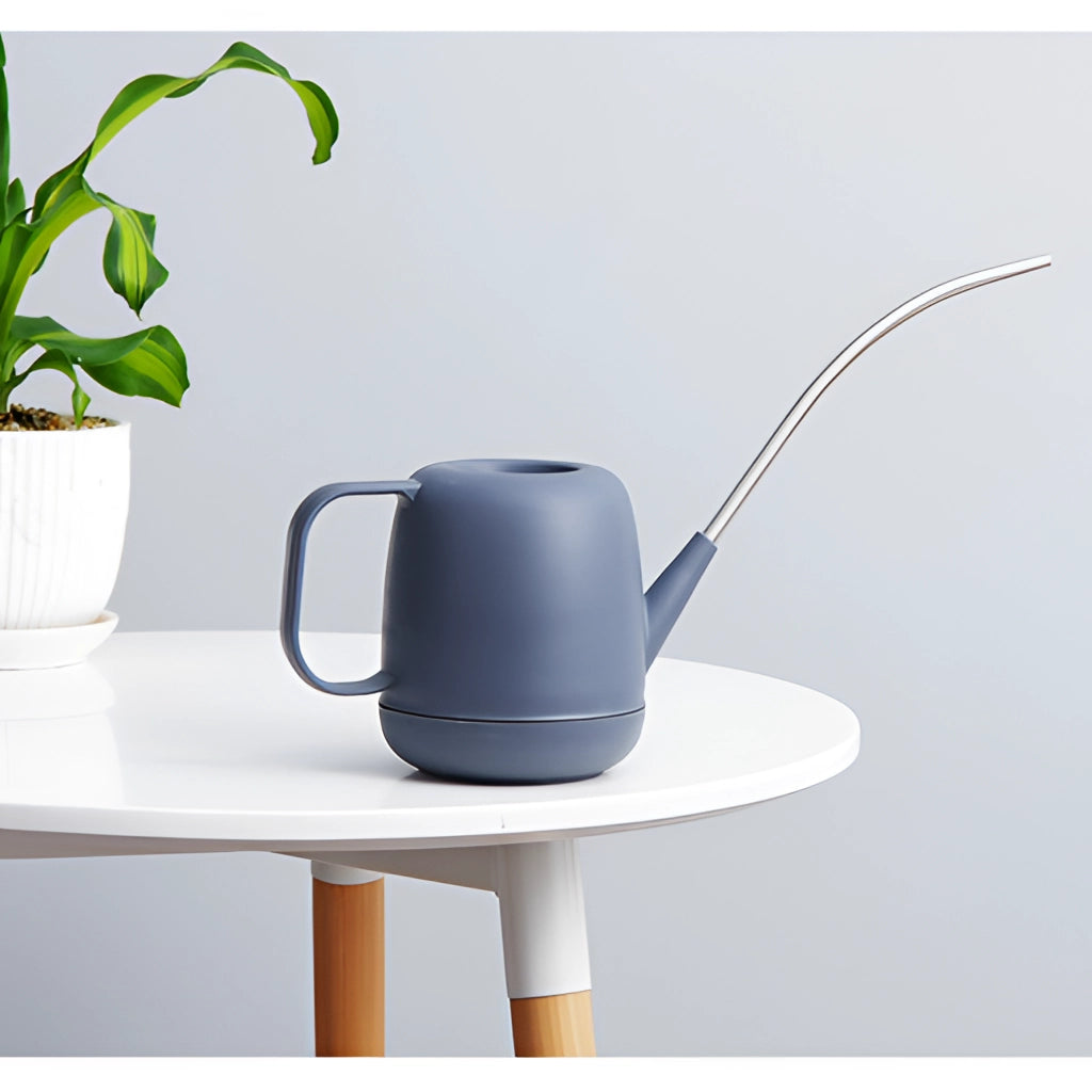 Modern and functional April Showers garden watering can placed next to green houseplants and flowerpots.