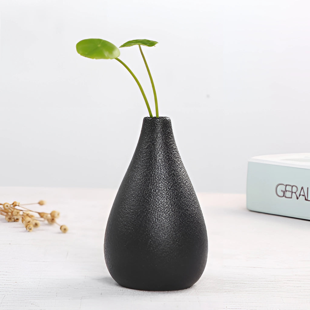 A sleek black ceramic vase filled with green plants, ideal for home and garden decor.