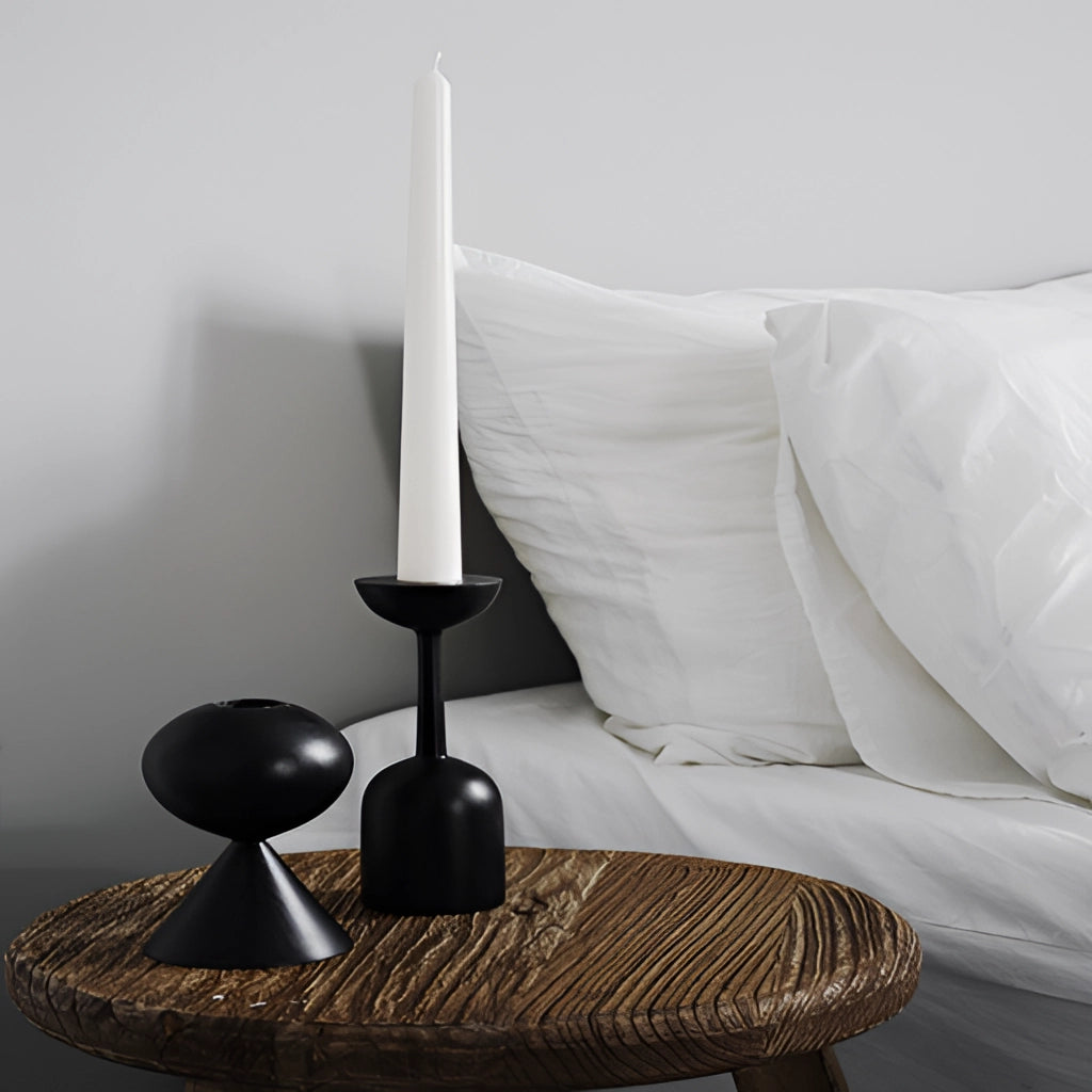 A set of black wooden candle holders placed on a grey hardwood floor in a cozy room setting.