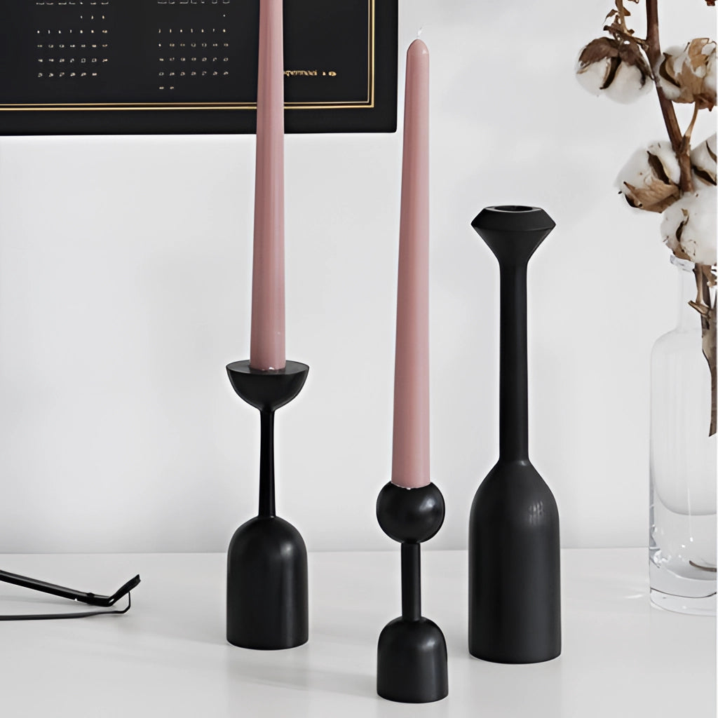 Set of black wooden candle holders displayed on a wooden shelf.