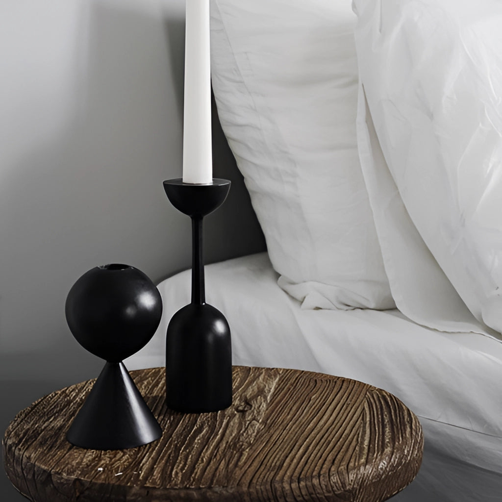Black wooden candle holder set displayed in a modern home decor setting with grey tones and hardwood flooring.