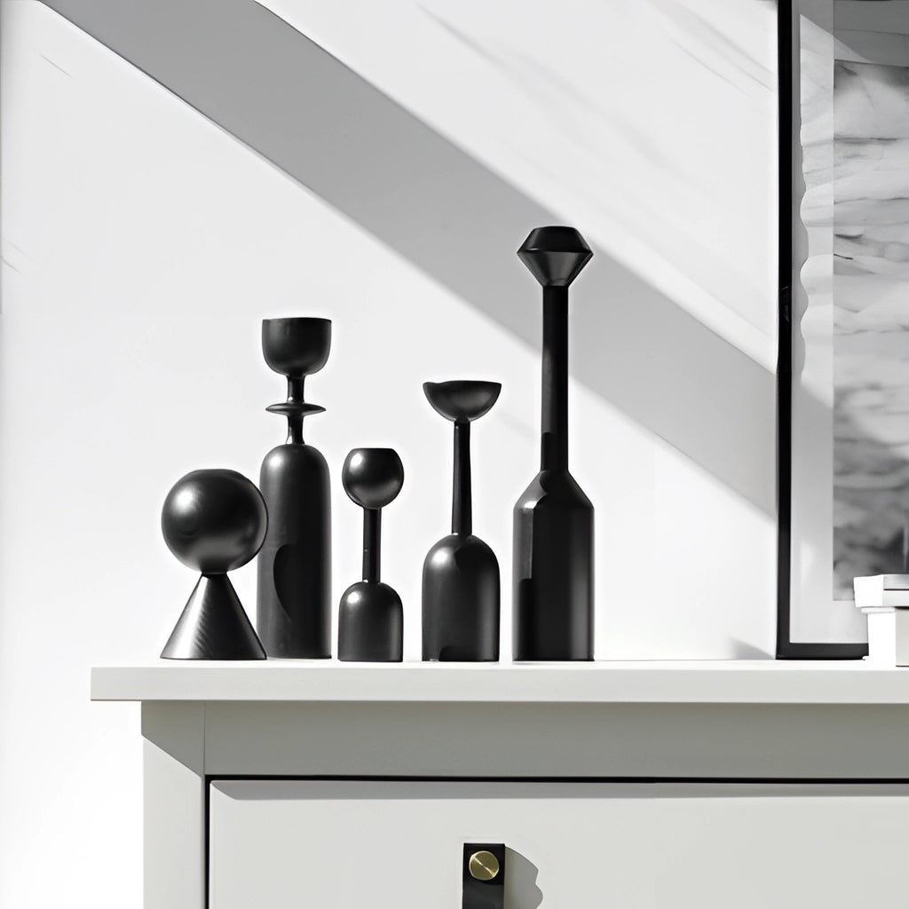 A set of black wooden candle holders in various shapes placed on a wooden shelf, part of a home decor setup.