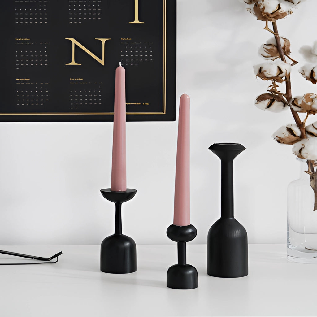 A set of black wooden candle holders arranged on a surface, showcasing their sleek design and rustic charm, suitable for home decor.