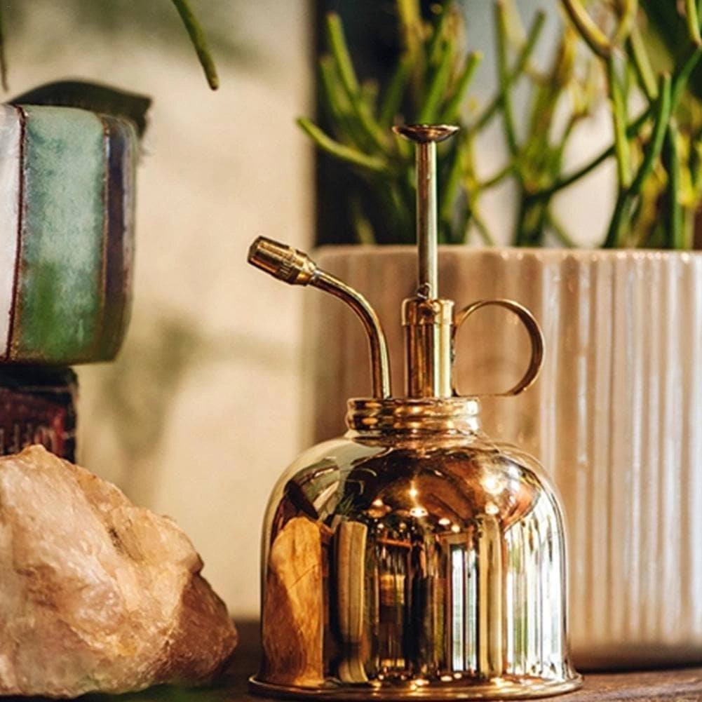 Vintage-style bronze plant mist sprayer made of brass with a glass bottle, used for watering plants.