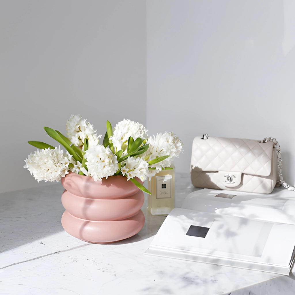 A ceramic round bubble glass planter vase on a table, holding a vibrant flower arrangement with green plants and colorful petals.