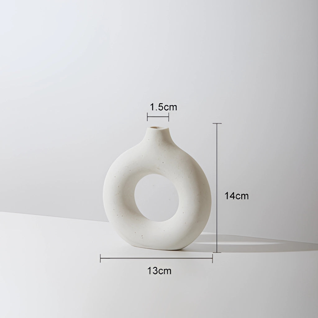 White small ceramic donut shape vase for modern home decor featuring an oval opening and smooth porcelain finish.
