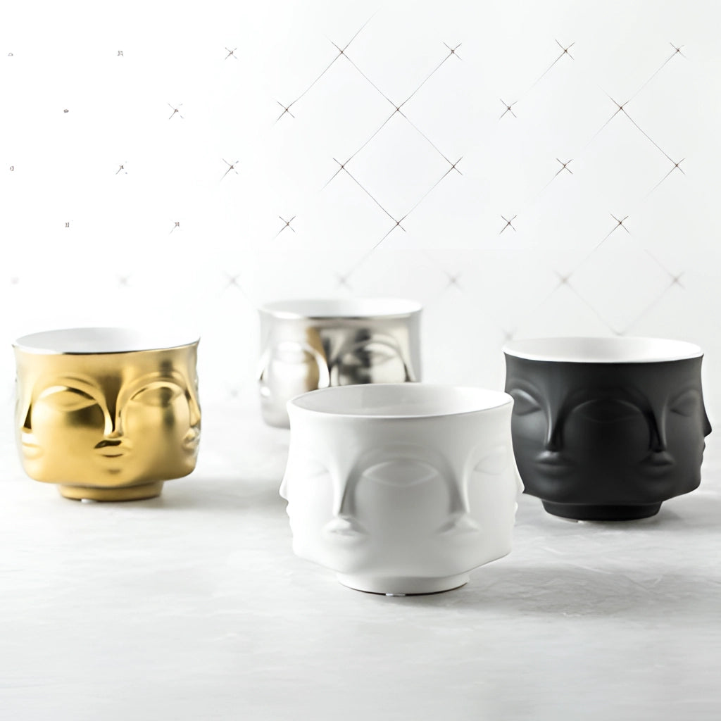 A modern ceramic flowerpot with a face design, ideal for succulents, placed on a surface.
