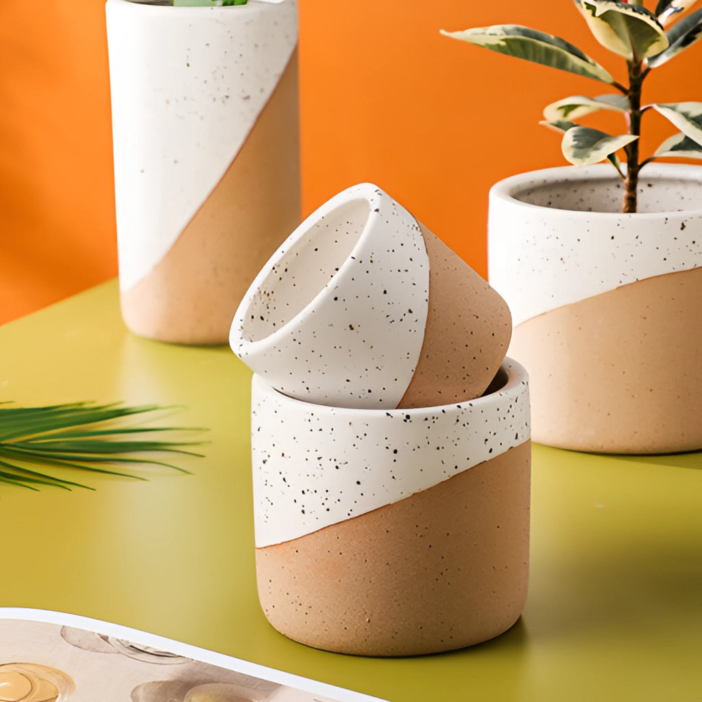 Small, medium, and large ceramic flowerpots in linen color, each containing houseplants with leaves.