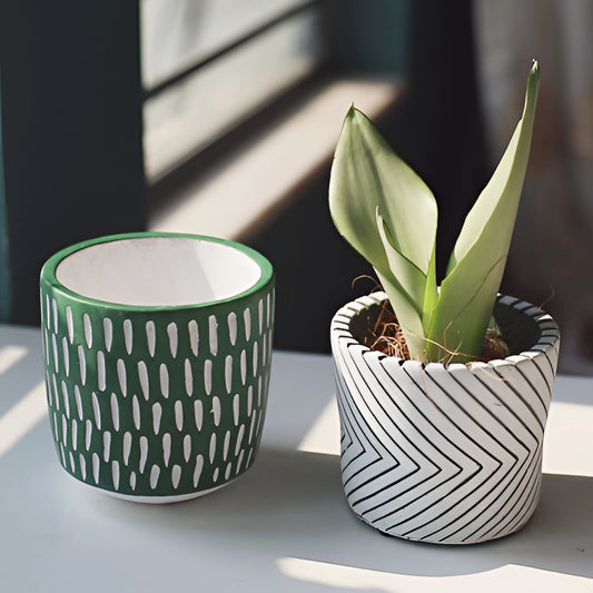 Hand-painted ceramic planters with textured designs, featuring vibrant colors and patterns, displayed with green houseplants.