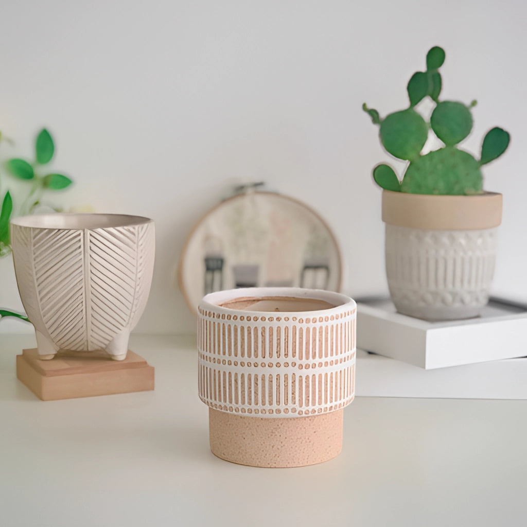 Ceramic Island Holiday Plant Pots on a wooden table with green houseplants.