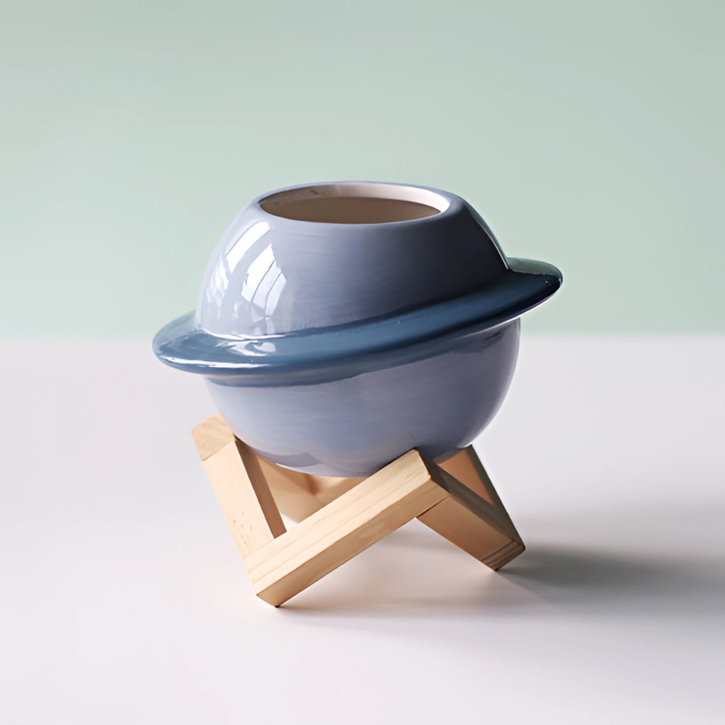 Ceramic plant pot featuring an astral galaxy design, resembling a helmet or hat, placed on a wooden surface.