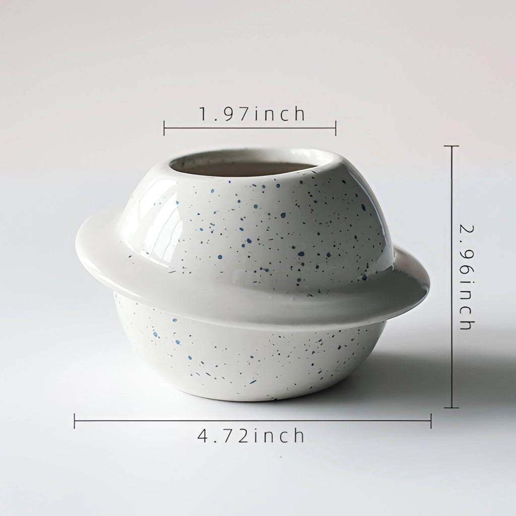 Ceramic plant pot with an astral galaxy design, featuring circular patterns and a glossy finish, displayed on a white surface.