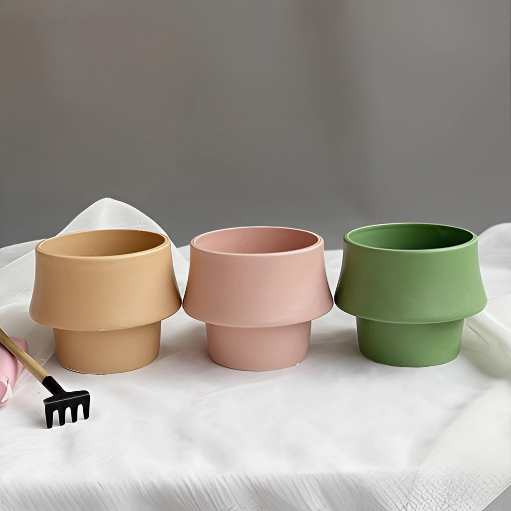A glazed ceramic planter in rosa, featuring Scandinavian style design, placed on a table.