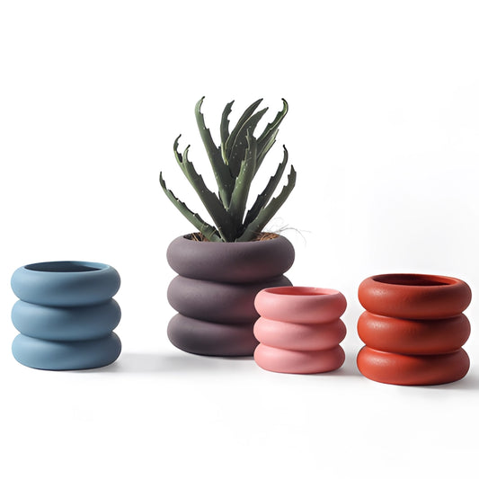 A ceramic round plant pot in a minimalist design, displayed on a wooden table.