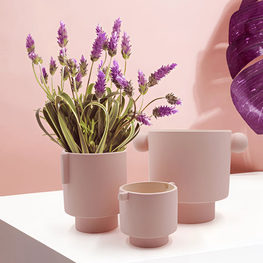 Hand-molded ceramic vase in earthy tones, Scandinavian design, with a houseplant and violet flowers.