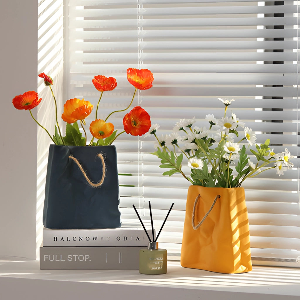 A ceramic vase with a shopping basket design, containing vibrant orange and yellow flowers, placed near a window.