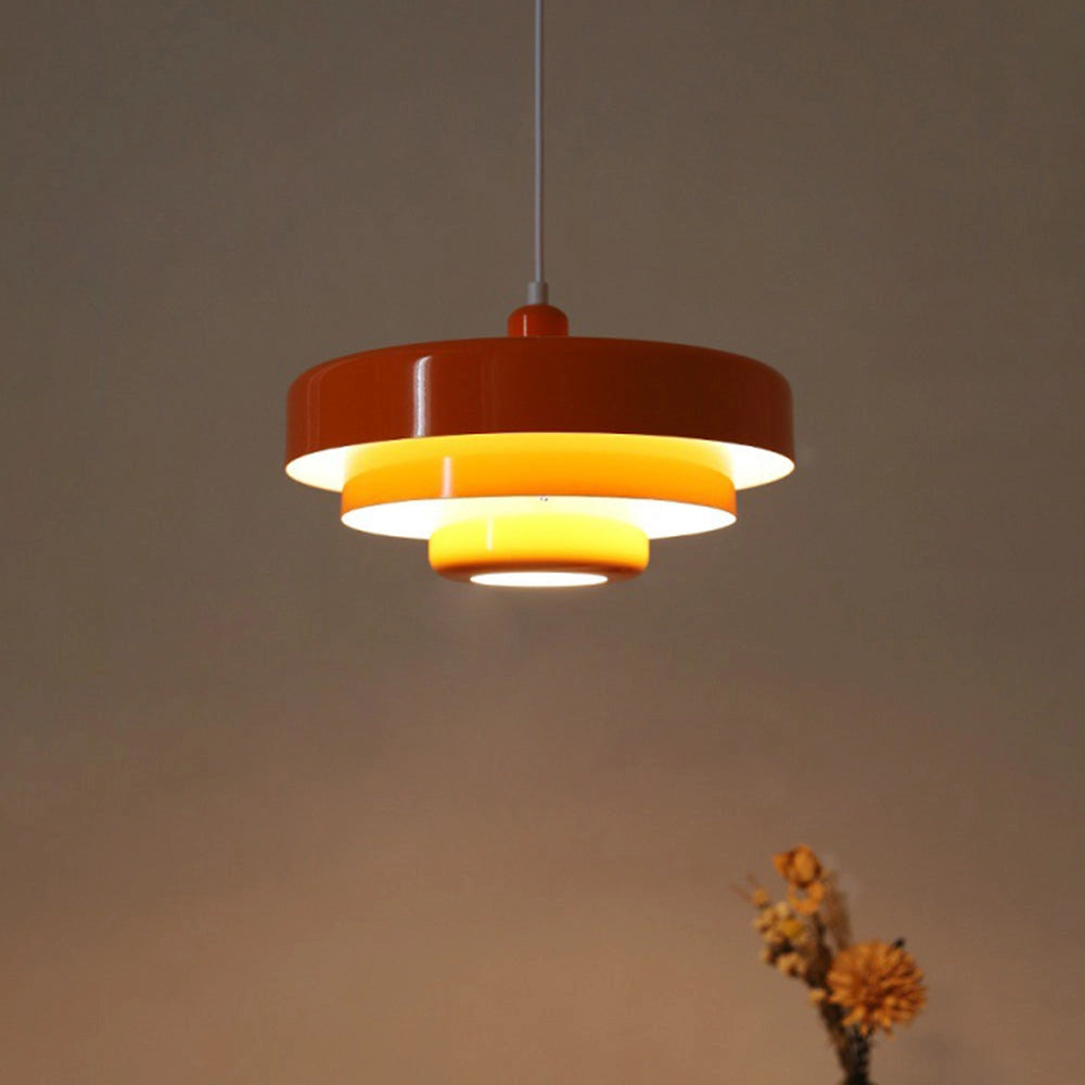 Modern metal pendant lamp with linked circle design, emitting warm amber light, hanging from the ceiling.