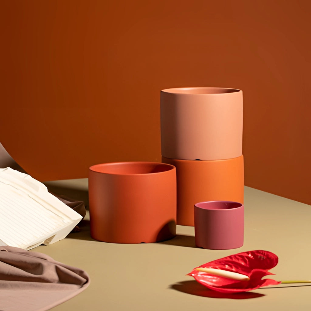 Colorful ceramic planter and saucer set on a wooden table in a room with office supplies and tissue paper nearby.