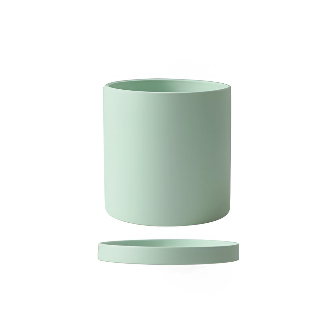 A large mint-colored ceramic planter and saucer set displayed on a table.