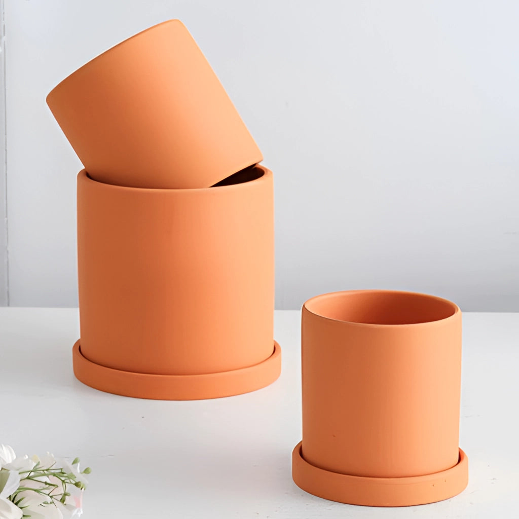 Colorful ceramic planter and saucer set featuring a vibrant orange design, displayed on a table.