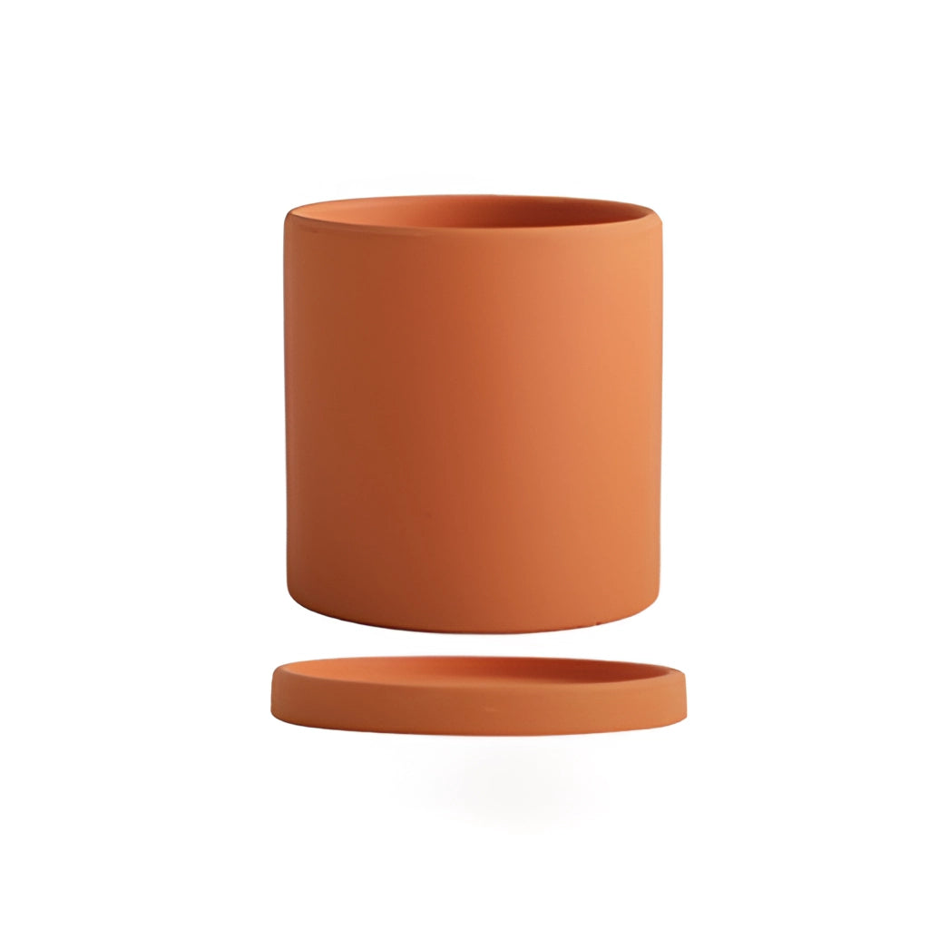 Large orange ceramic planter and saucer set on a wooden surface.