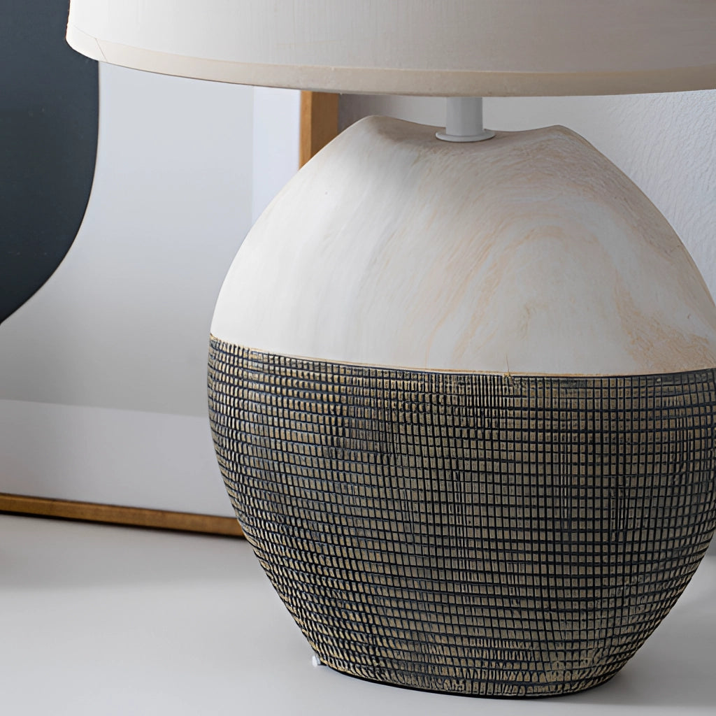 Contemporary wooden table lamp with a beige lampshade, placed on a rectangular wooden surface in a cozy living room setting.