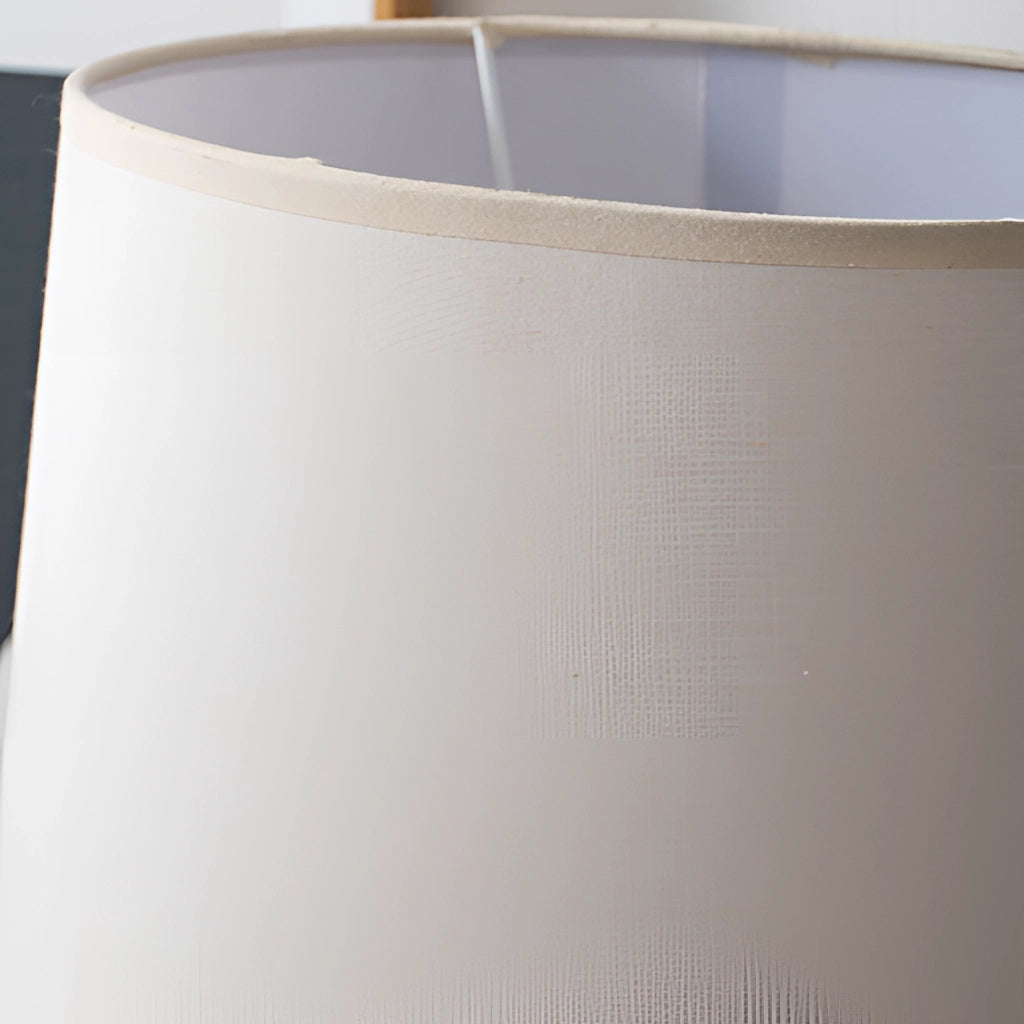 A contemporary table lamp with a beige rectangular lampshade, wooden base, and metal accents, placed in a living room setting.