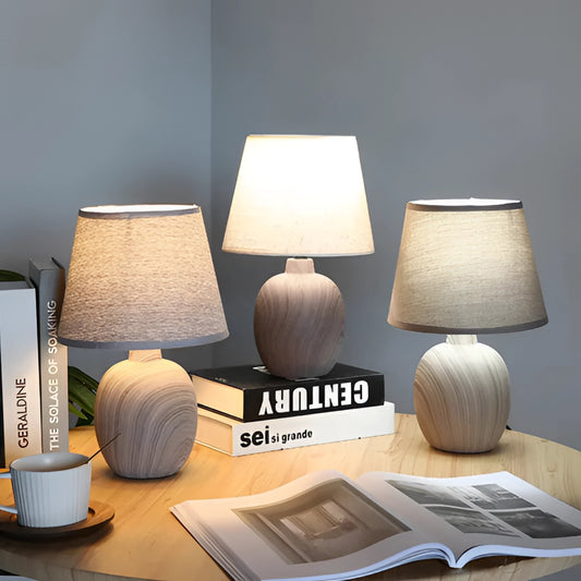 Contemporary rechargeable table lamp with unique style, featuring a wooden base and textile shade, placed on a wooden surface in a modern interior design setting.