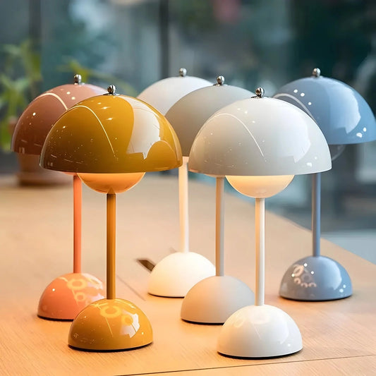 Cordless flowerpot table lamp with touch sensor on a wooden table, glowing with warm orange light, surrounded by decorative plant elements.