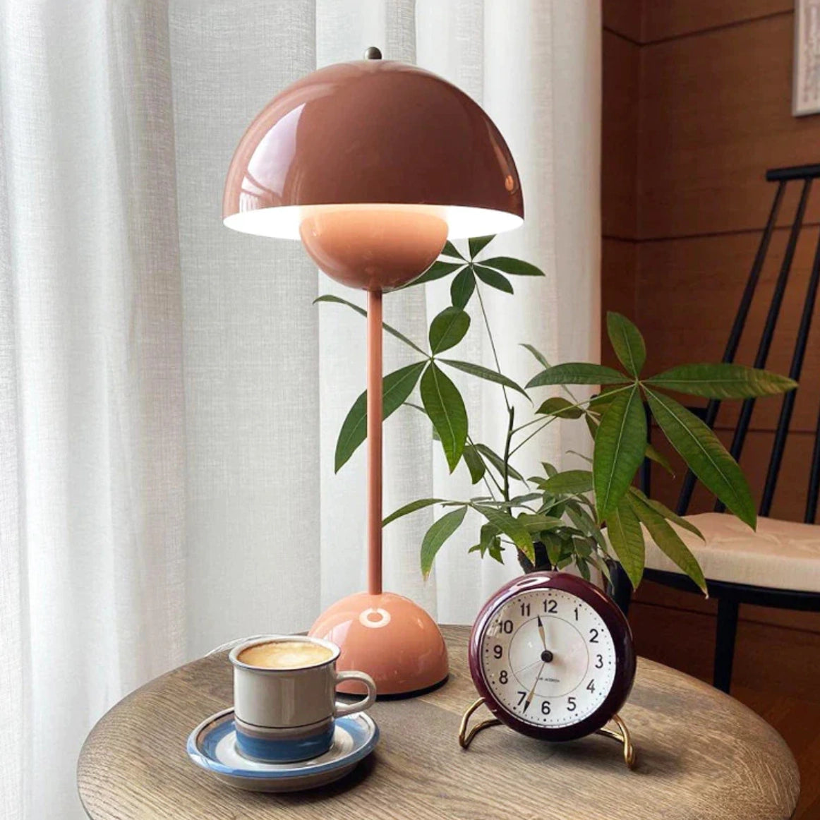 Cordless flowerpot table lamp with touch sensor on a wooden table, surrounded by tableware and a cup.