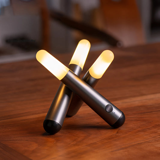 Cordless Kinetic Rotation LED Table Lamp with Frosted finish on a wooden table surrounded by office supplies including pens and stationery.