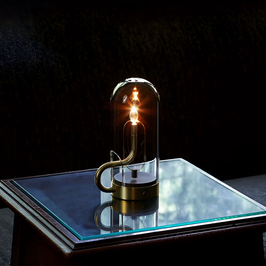 Cordless LED table lamp on a wooden table, designed to resemble a candle with a soft flame-like glow, providing ambient lighting.