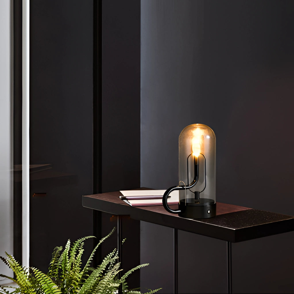 Cordless LED table lamp on a wooden table beside a small plant, providing ambient lighting in a modern interior setting.