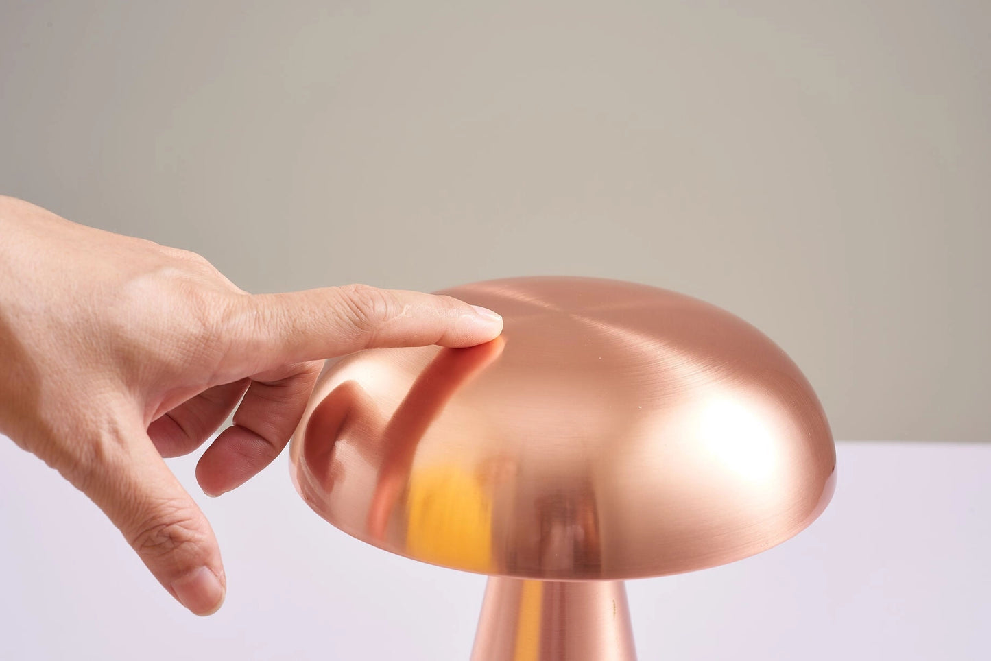 Cordless Mushroom LED Table Lamp with steepless dimming feature and long battery life placed on a wooden surface, with a hand adjusting the lamp's brightness using gesture control.