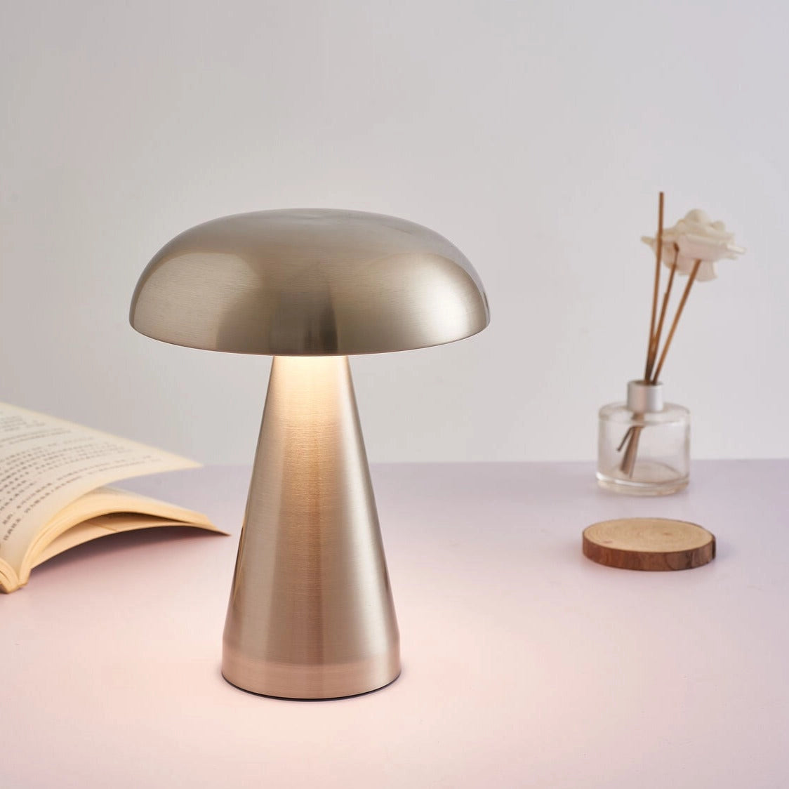 Cordless mushroom-shaped LED table lamp with steepless dimming feature on a wooden table, accompanied by a metal chair.