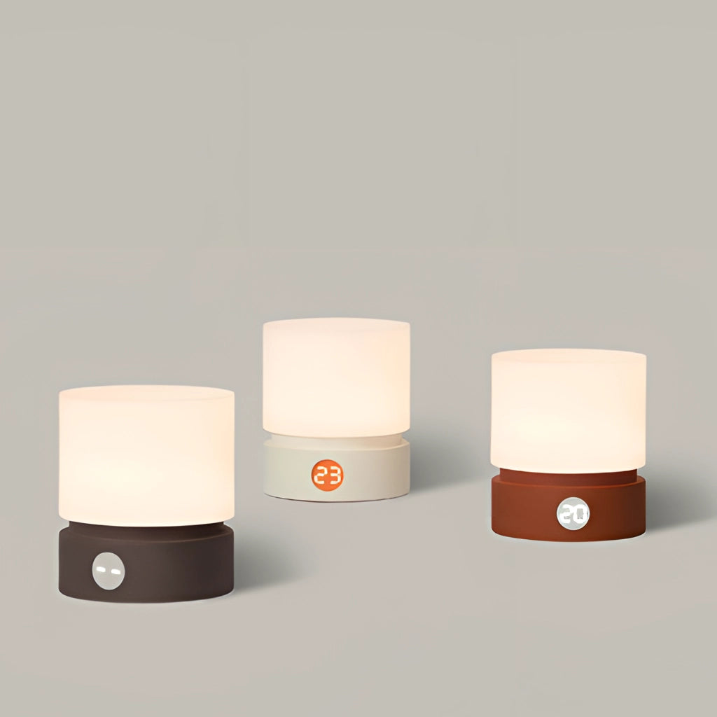 A sleek cordless table lamp with a rectangular base, featuring adjustable brightness settings, placed on a wooden surface next to a small potted plant, and various decorative items including jewelry and fashion accessories.