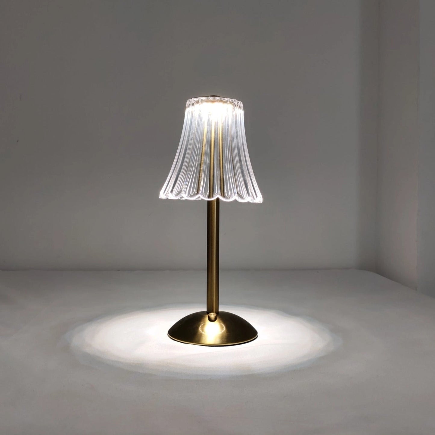 Cordless table lamp with supreme durability and beautiful design on a wooden surface, surrounded by a small plant and artistic decor, featuring natural materials and glass elements.