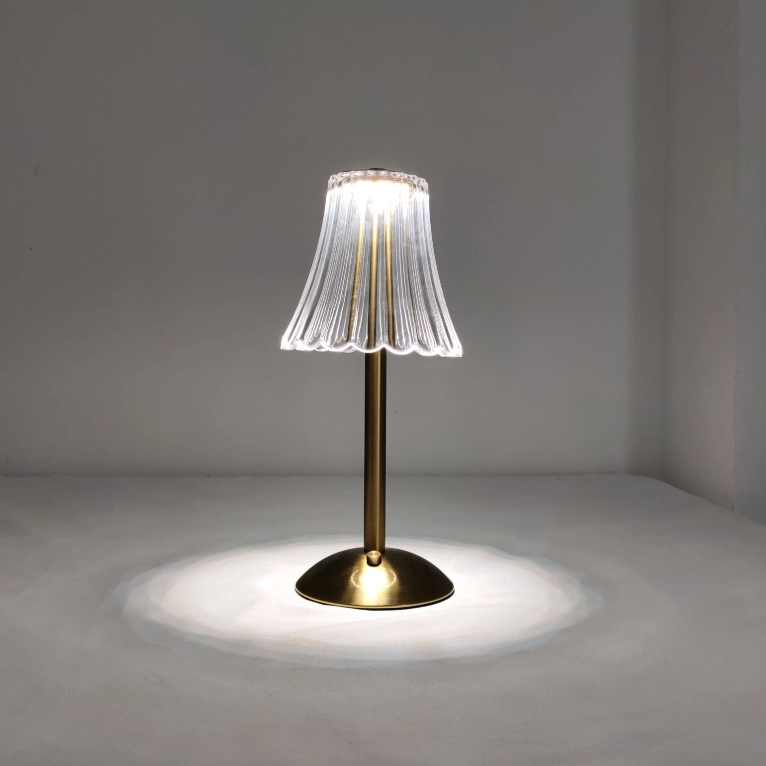 Cordless table lamp with supreme durability and beautiful design on a wooden surface, surrounded by a small plant and artistic decor, featuring natural materials and glass elements.