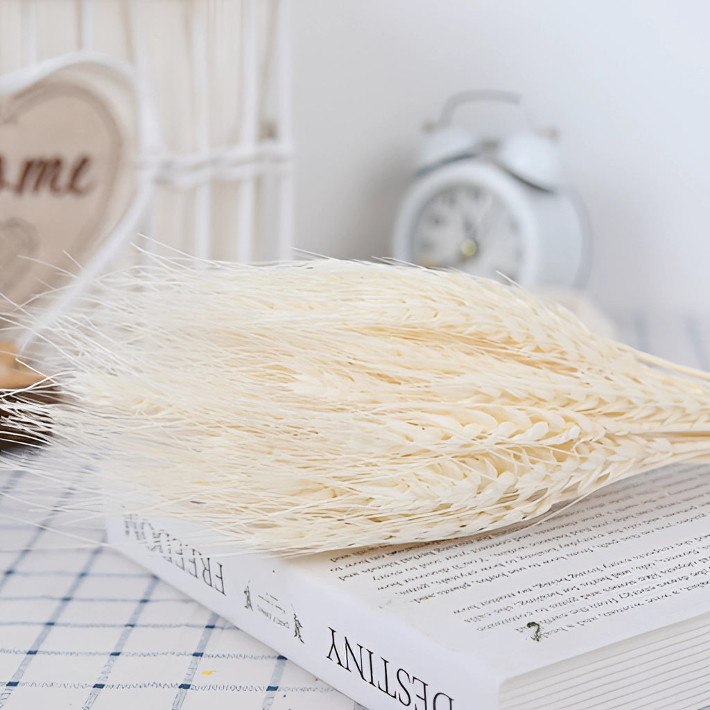 A 30-piece set of dried pampas grass flowers arranged in a vase on a wooden table, accompanied by a decorative clock and linens, perfect for interior decoration.