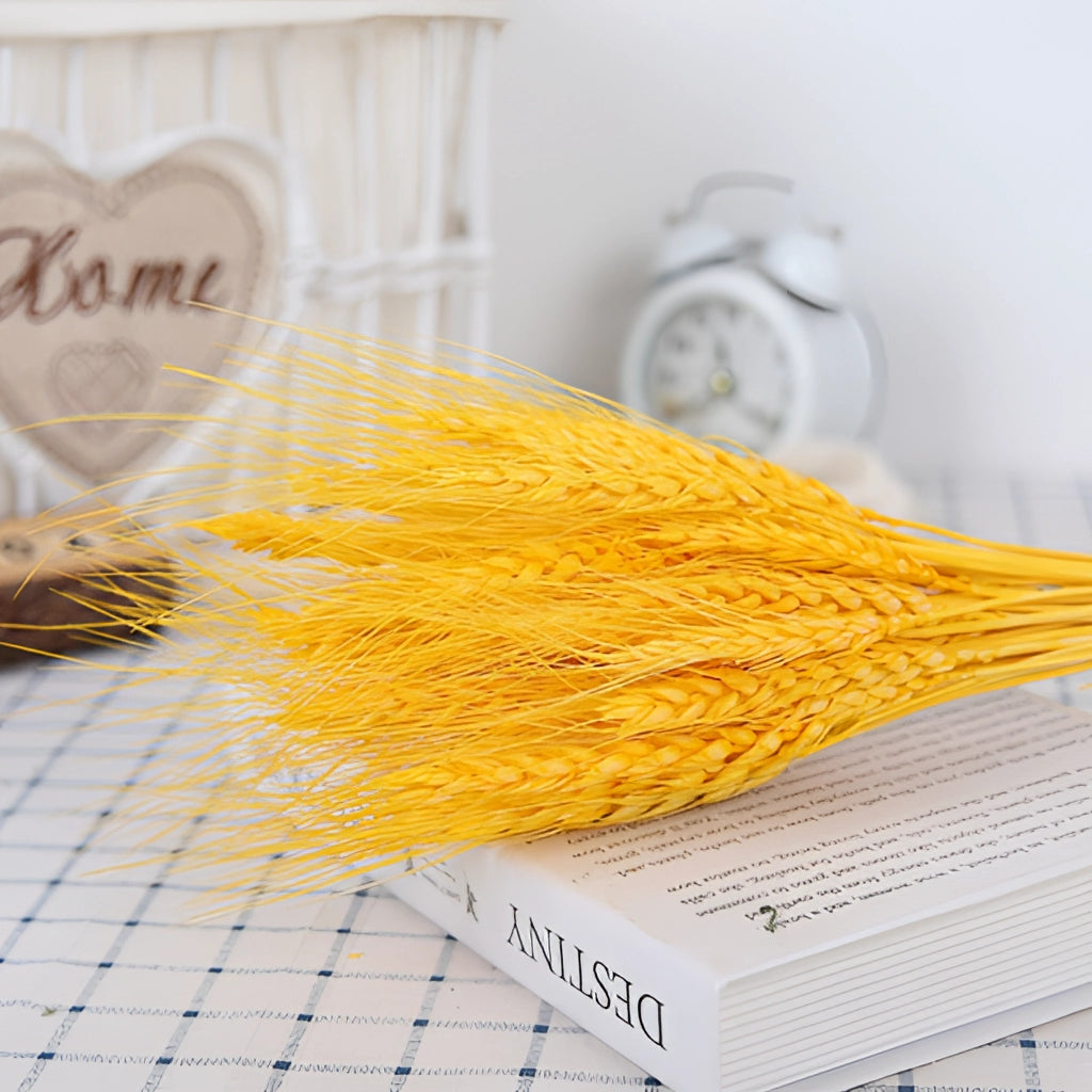 A 30-piece set of dried pampas grass flowers arranged as an interior decoration, featuring light orange and yellow hues, displayed alongside a clock on a wooden surface.
