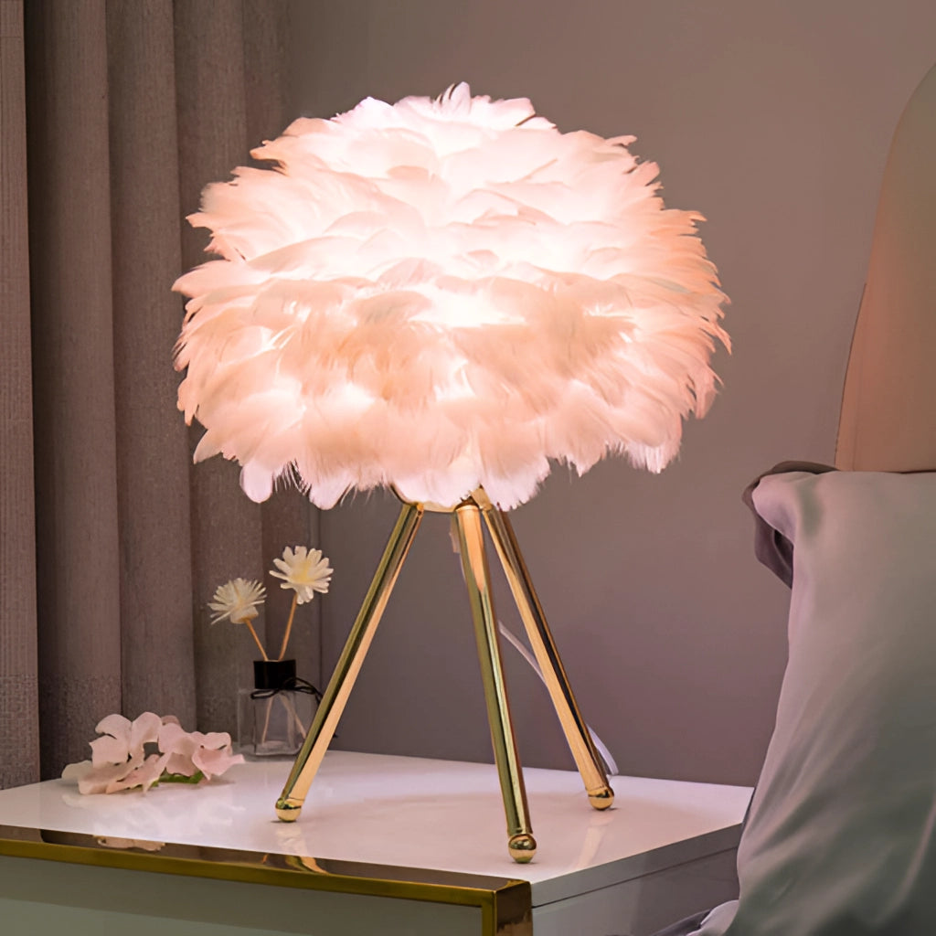 A Feather LED Table Lamp with dimmable lighting placed on a table beside a vase of artificial flowers.